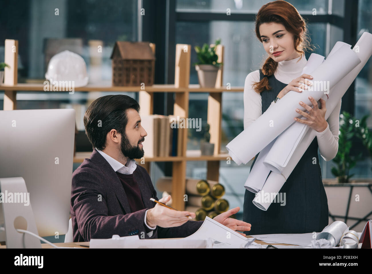 two architects discussing and working with blueprints in office Stock Photo