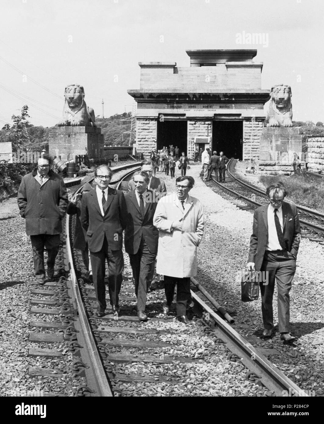 In between the the railway line are (l-r) Fred Mulley, Minister of Transport, George Thomas, Secretary of State for Wales, and Cledwyn Hughes, Minister of Agriculture, inspect the fire-damaged tubular Britannia Bridge over the Menai Straight. Stock Photo