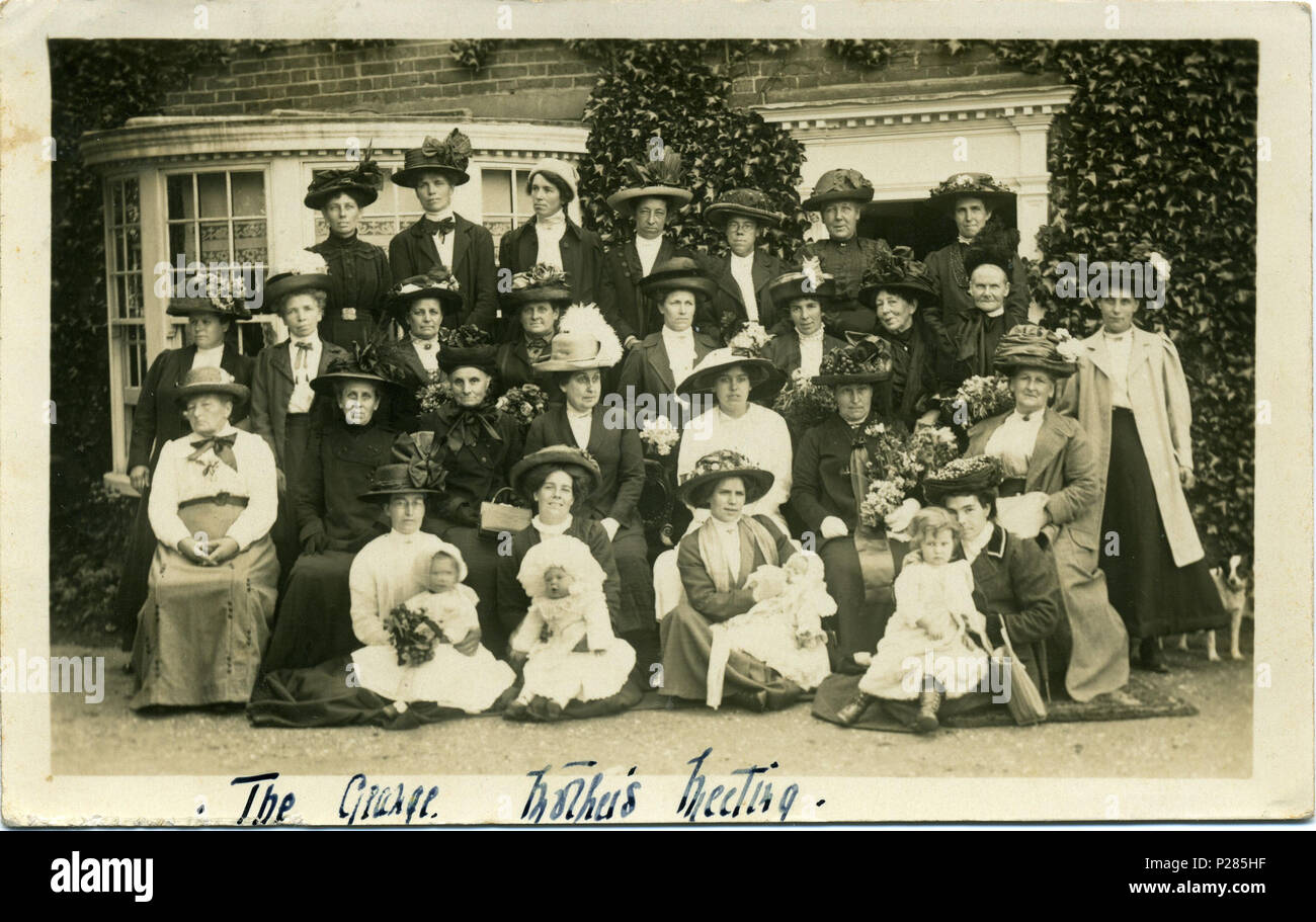 . Postcard photo taken in 1913 of a Mothers' Meeting group at The Grange, 75 Reculver Road, Herne Bay, Kent, England. The building was listed Grade II in 1951: further details here. As of 2011 the building was a care home. The postcard is postmarked Herne Bay, 1913. The photographer was Fred C. Palmer of Tower Studio, Herne Bay, Kent 1903-1922, who is believed to have died 1936-1939. Points of interest  Most of the women have flowers; they have possibly had a flower-arranging class as part of their treat? The standing woman on the far right appears to be holdiing the little dog's lead; dogs we Stock Photo