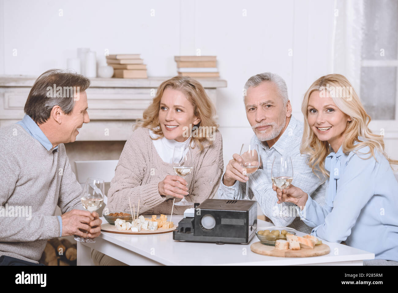 friends sitting at table with food and projector in room interiorn Stock Photo Alamy