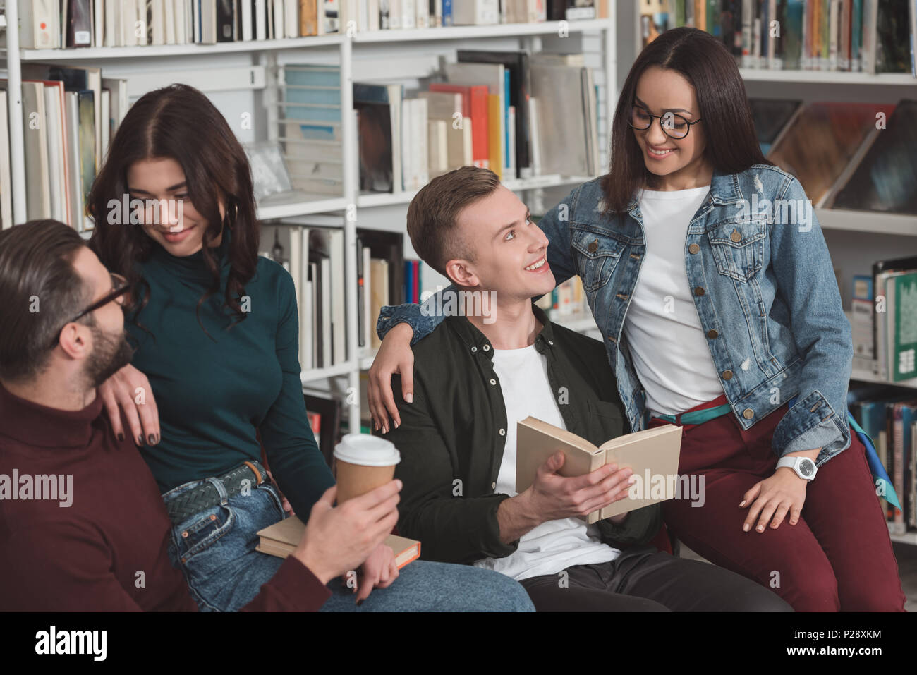 multicultural couples sitting on chairs in library Stock Photo - Alamy