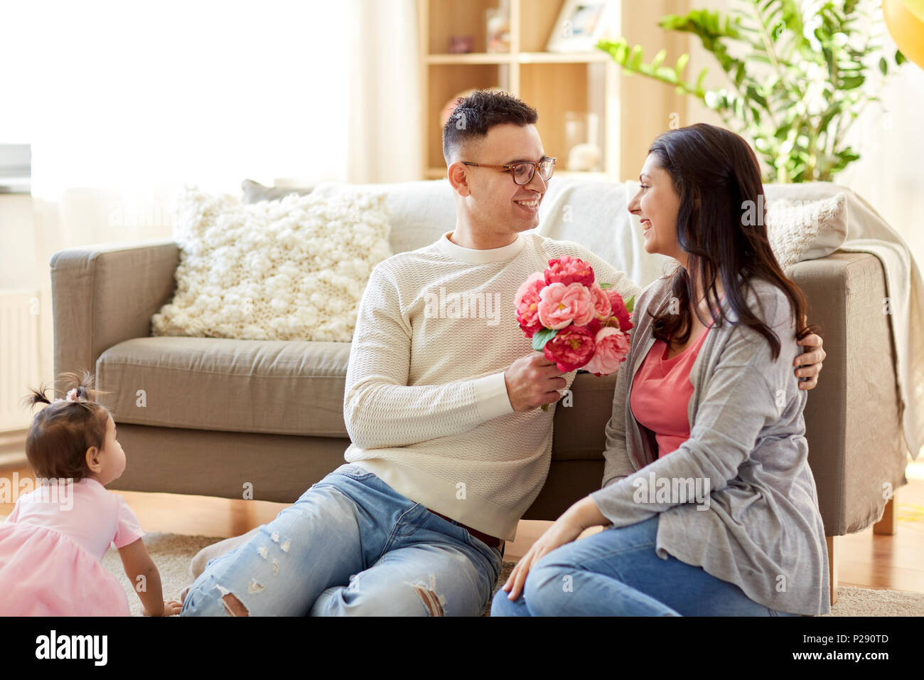 happy husband giving flowers to his wife at home Stock Photo