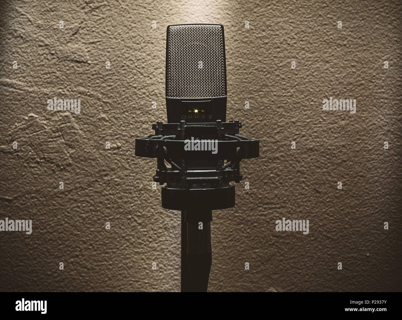 Closeup of condenser microphone on stand in front of a wall. Stock Photo