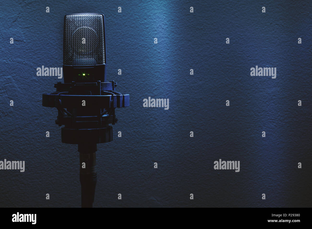 Closeup of condenser microphone on stand in front of a wall. Stock Photo