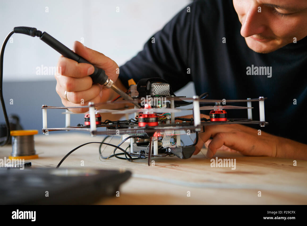 Photo of young man with soldering iron chipping mechanism in room Stock Photo Alamy