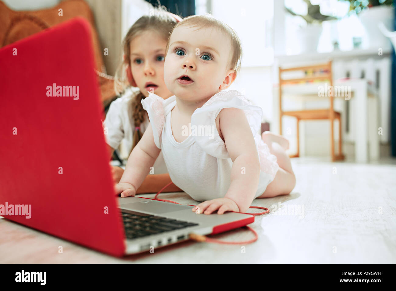 Portrait of little baby girl looking at camera with a laptop Stock ...