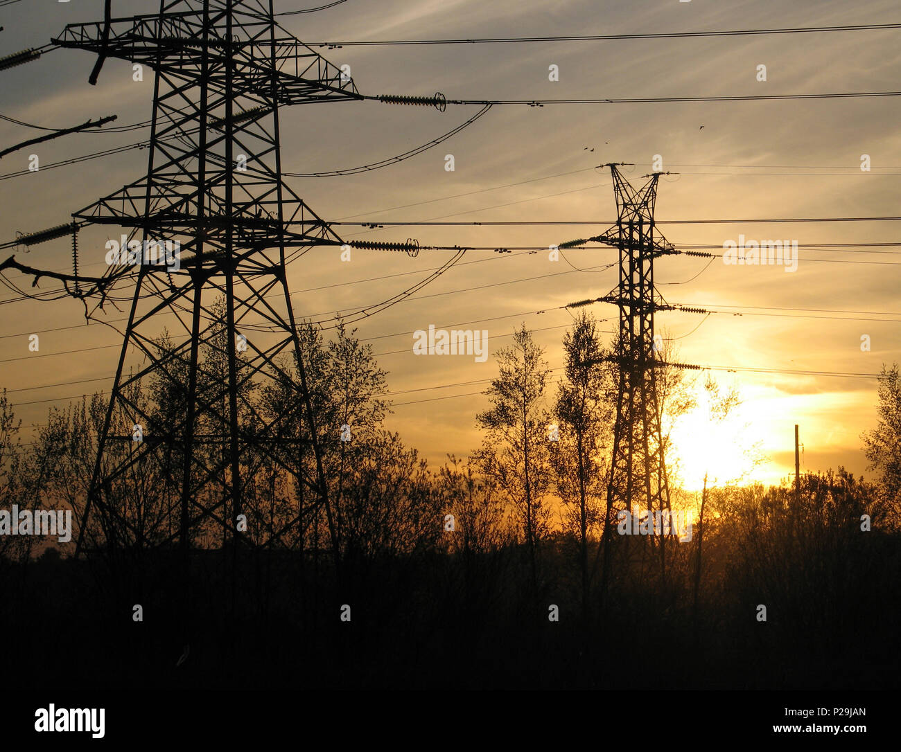 High voltage electric towers in the sunset out of the city Stock Photo ...