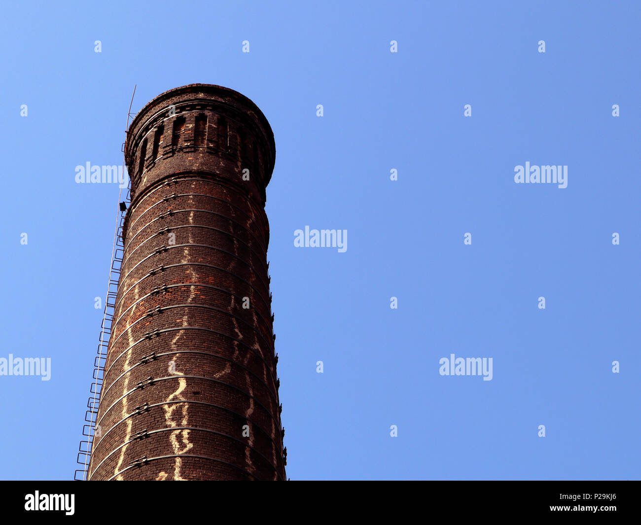 Old brick factory smoke stack against blue sky, bottom view, may be used as background Stock Photo