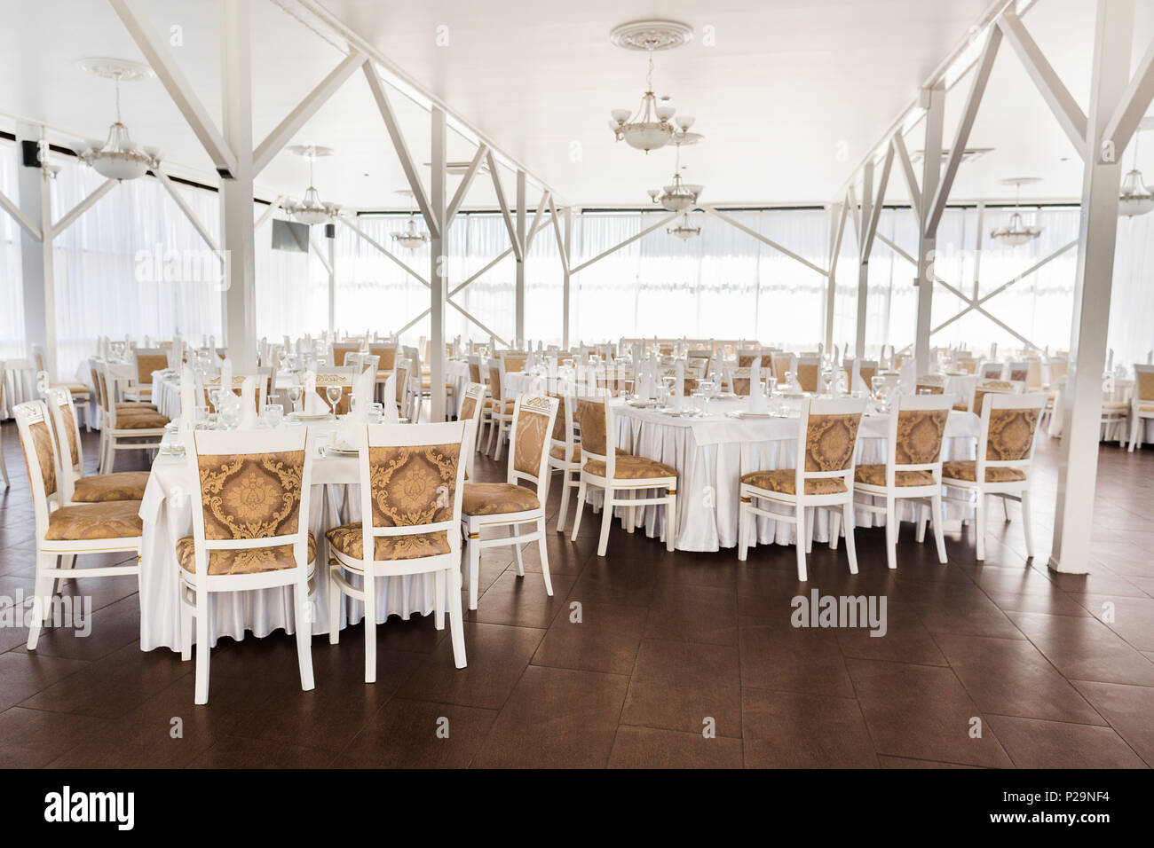 catering, party, engagement concept. there is spacious hall of the restaurant decorated in white coloures for happy day of loving couple, all tables a Stock Photo