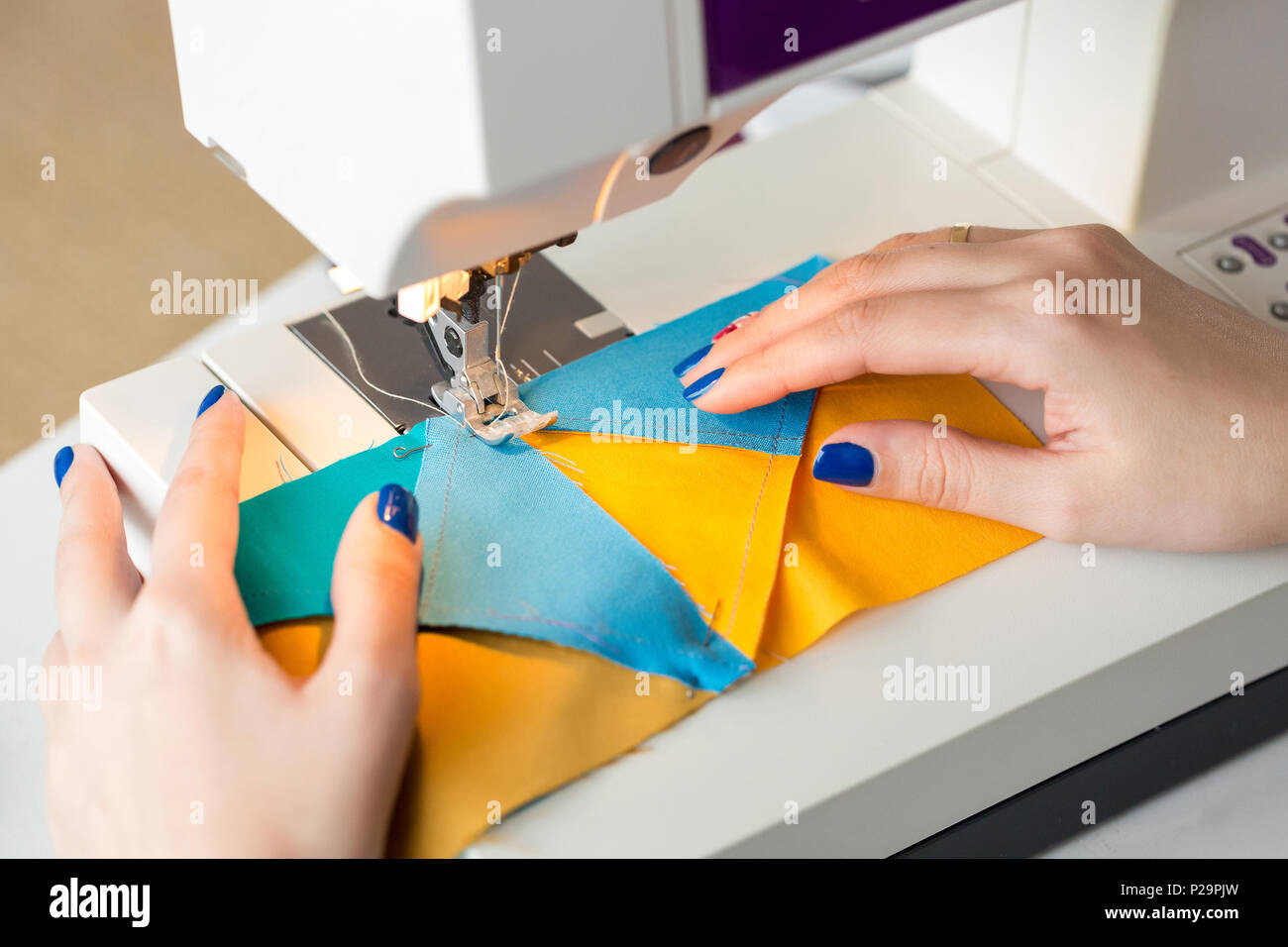 equipment, clothing, hobby concept. there is a close up of delicate arms of dressmaker who is working at the table with help of sewing machine, she is Stock Photo