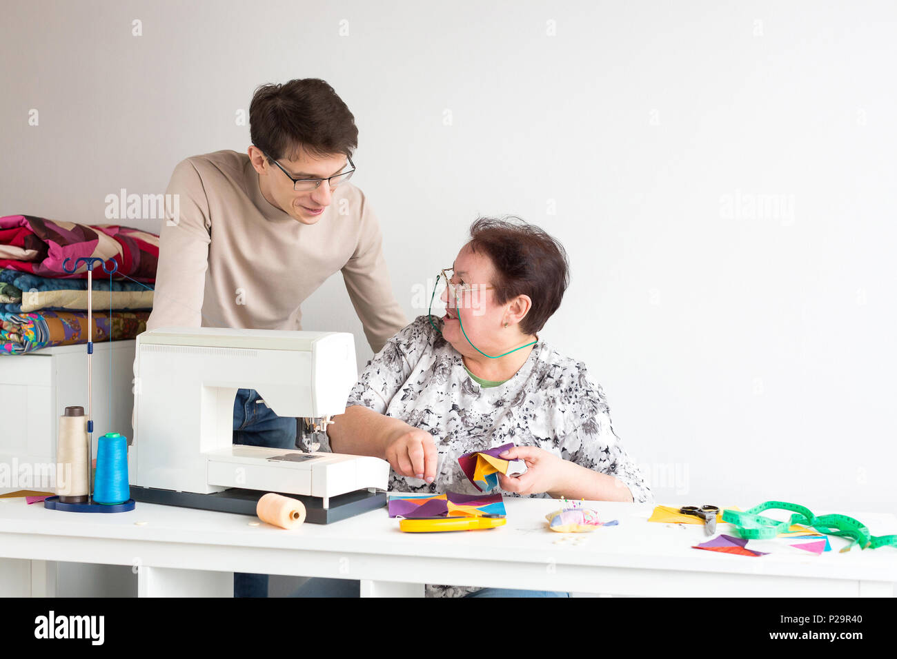 small business, design, manufactoring concept. by the old laughing woman there is a man, he is dressed in light sweater and eyeglasses, man is watchin Stock Photo