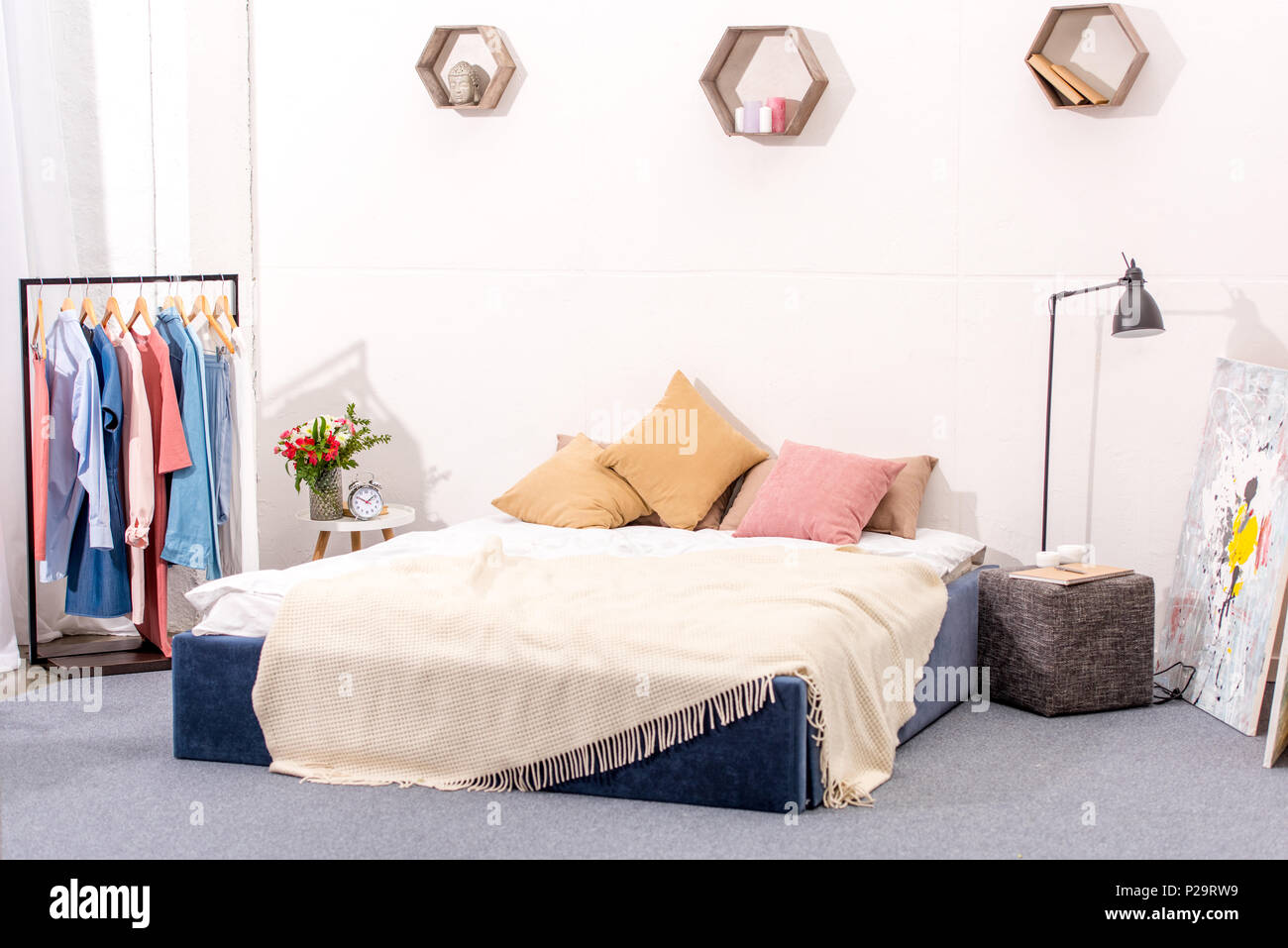 interior of bedroom with stylish decor and hanger full of various ...