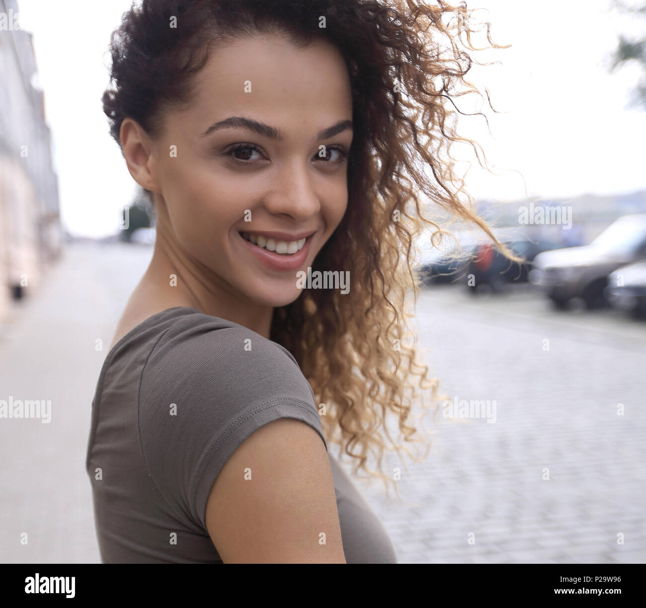 Young woman with afro hairstyle smiling in urban background Stock Photo ...