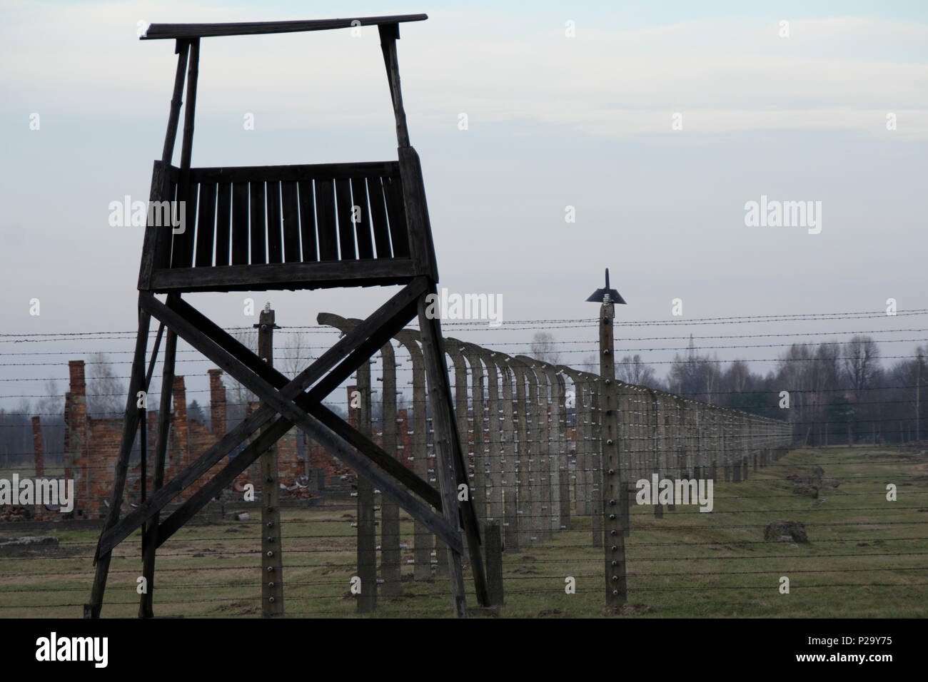 Guard tower sitting along a once electrified fence at Auschwitz-Birkenau on sunset Stock Photo