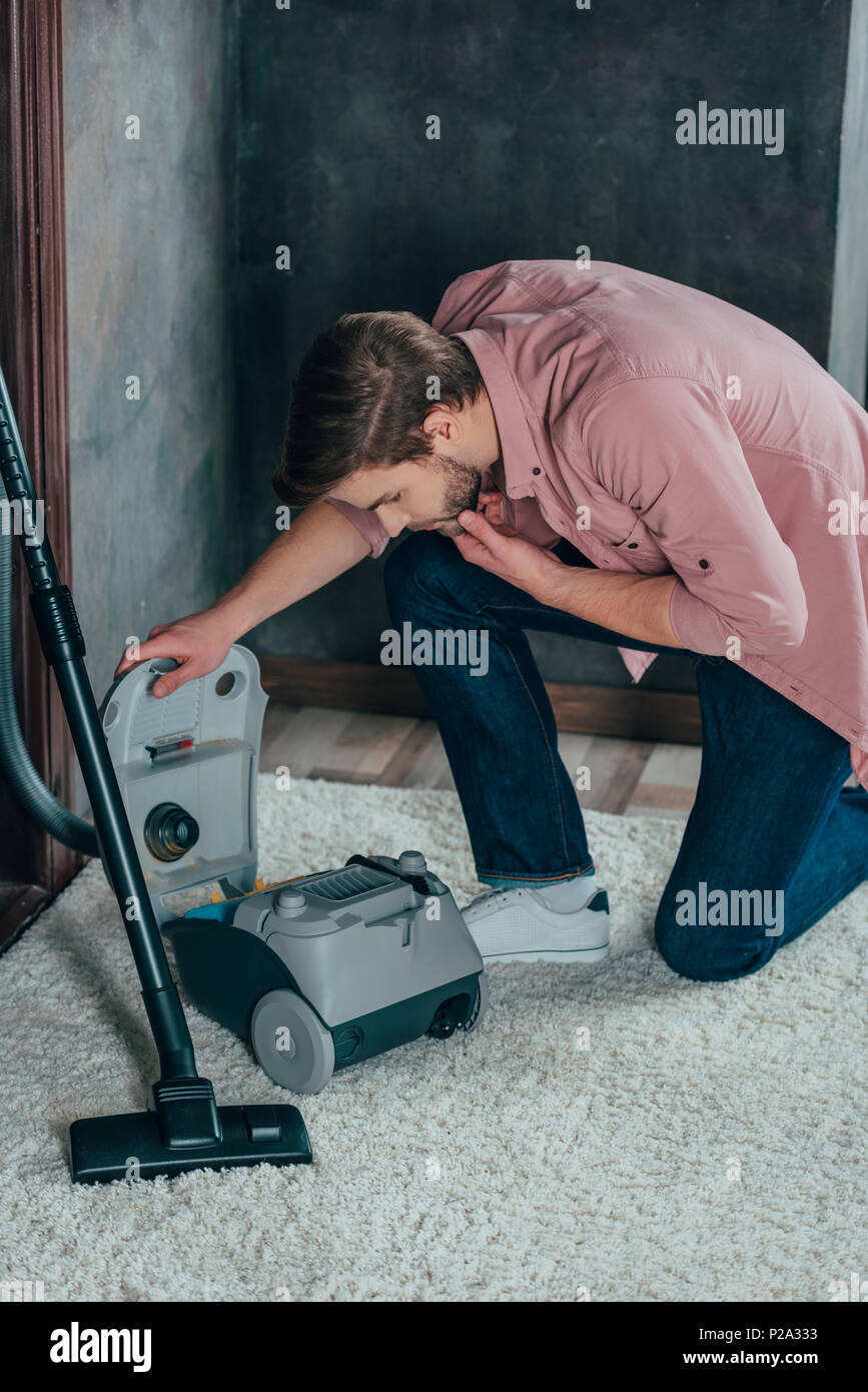 young man looking at broken vacuum cleaner at home Stock Photo Alamy
