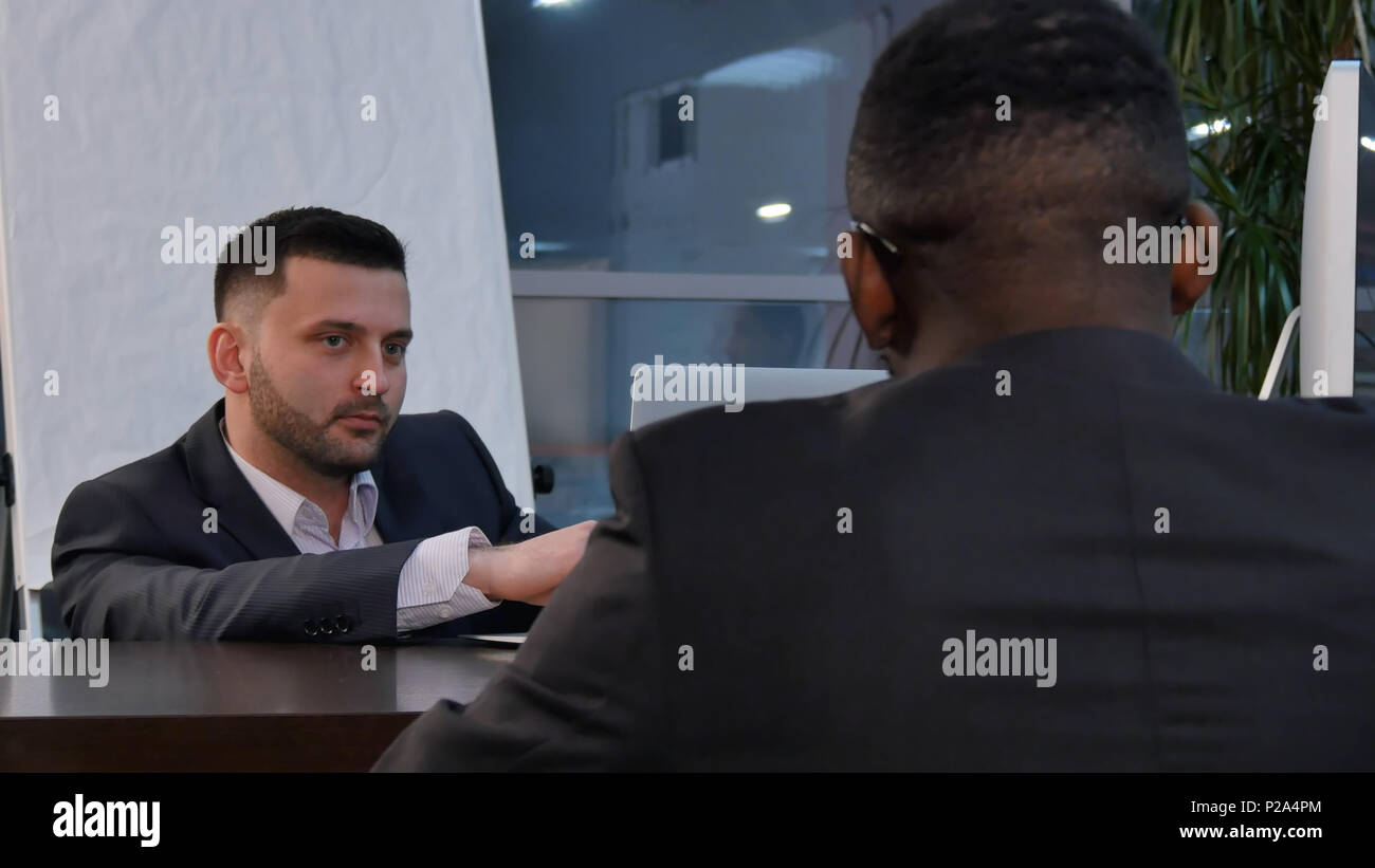 Two young businessmen discussing project at meeting Stock Photo