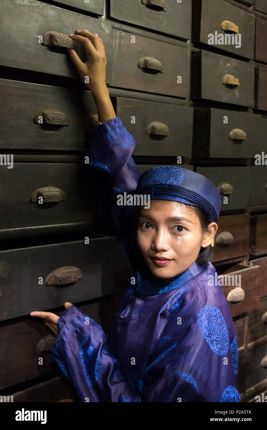 Asian pharmacist working at oriental pharmacy from the 19th century. Woman in traditional costume eastern druggist in the ancient drug store. Stock Photo