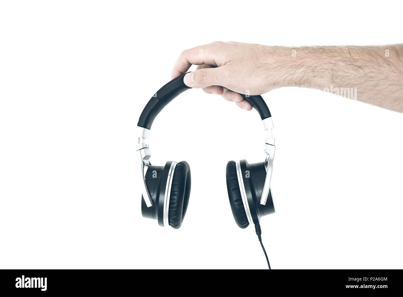 hand holding stereo headphones against white wall Stock Photo