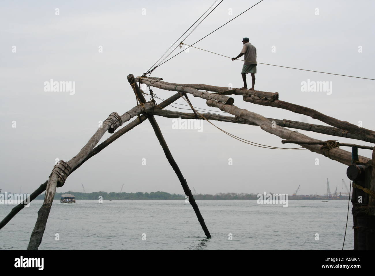 Indian fisherman balancing with rope and wood fixing Chinese fishing net Stock Photo