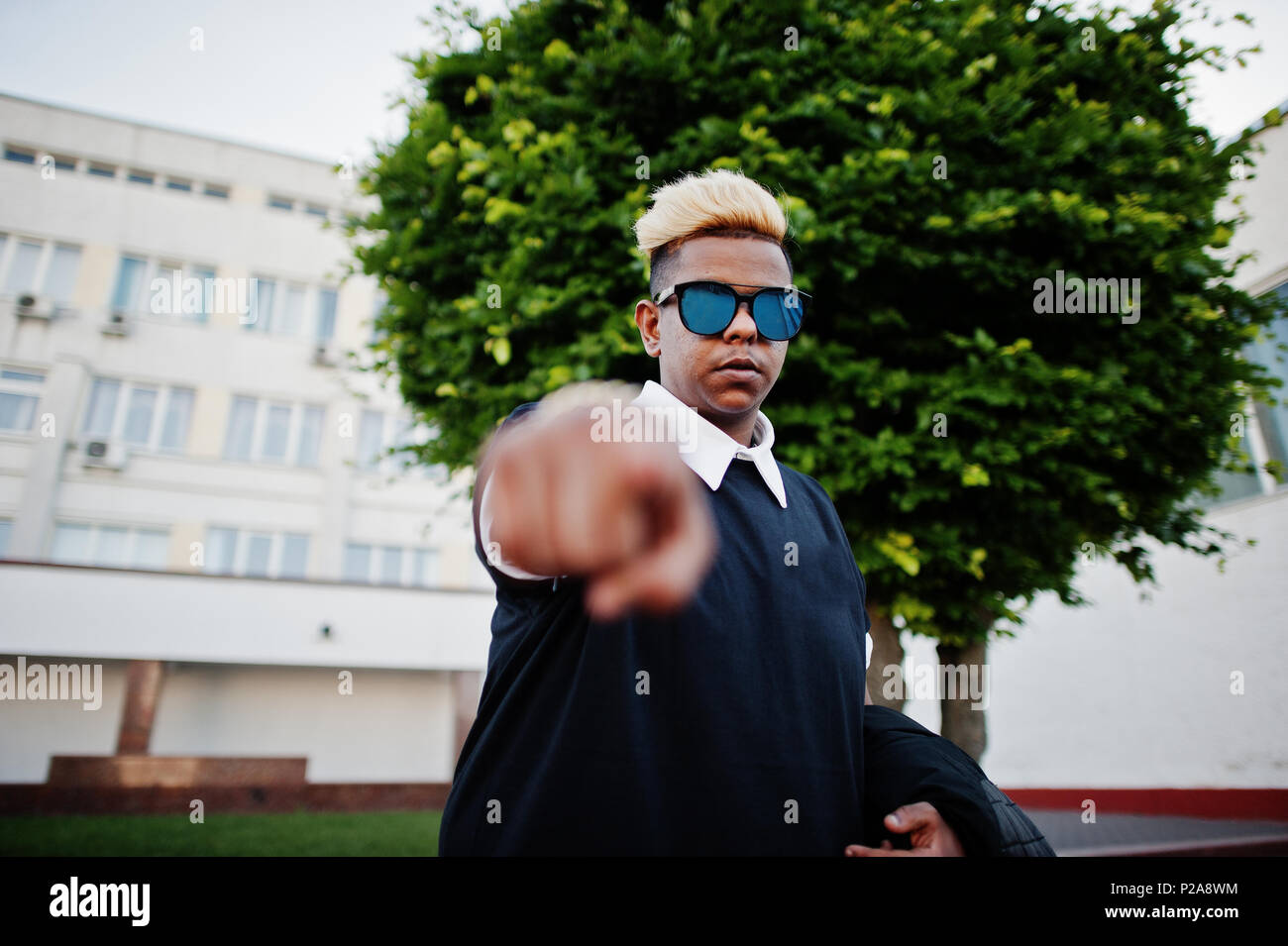 Stylish arabian muslim boy with originally hair and sunglasses posed on streets and show finger at camera. Stock Photo