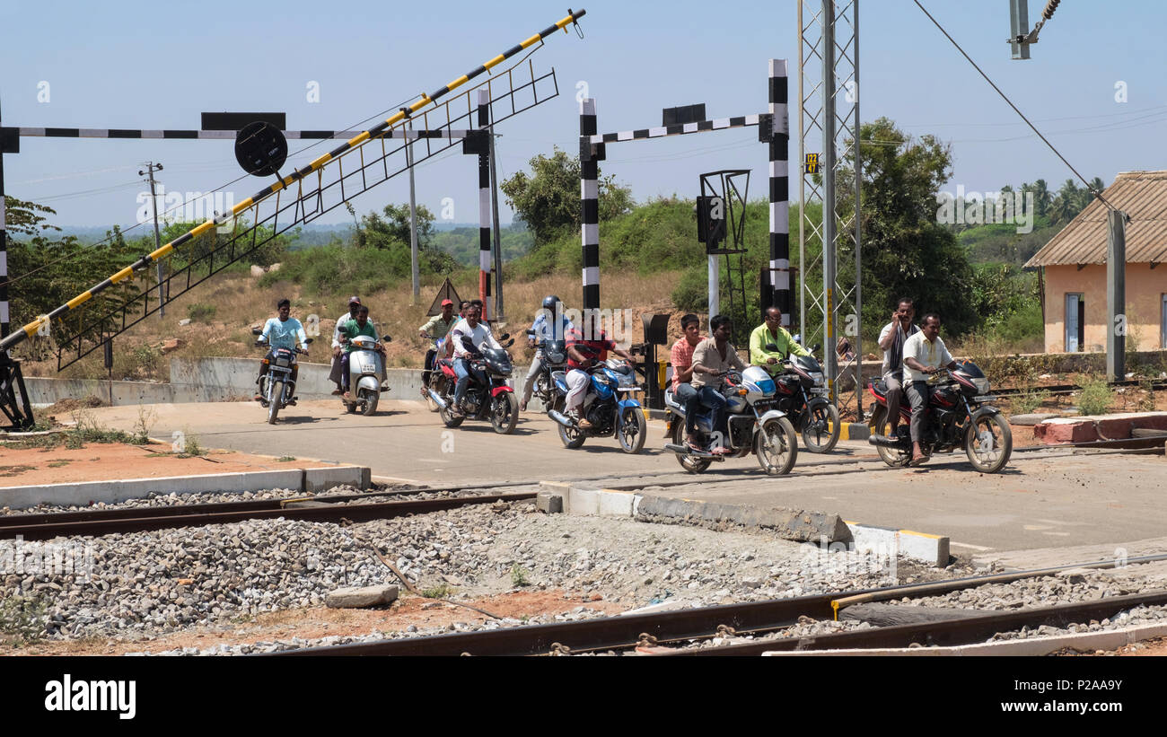 Shrirangapattan, India - March 2, 2018: Motorcyclists on a level crossing outside Srirangapatnam railway station immediately after a train has passed Stock Photo