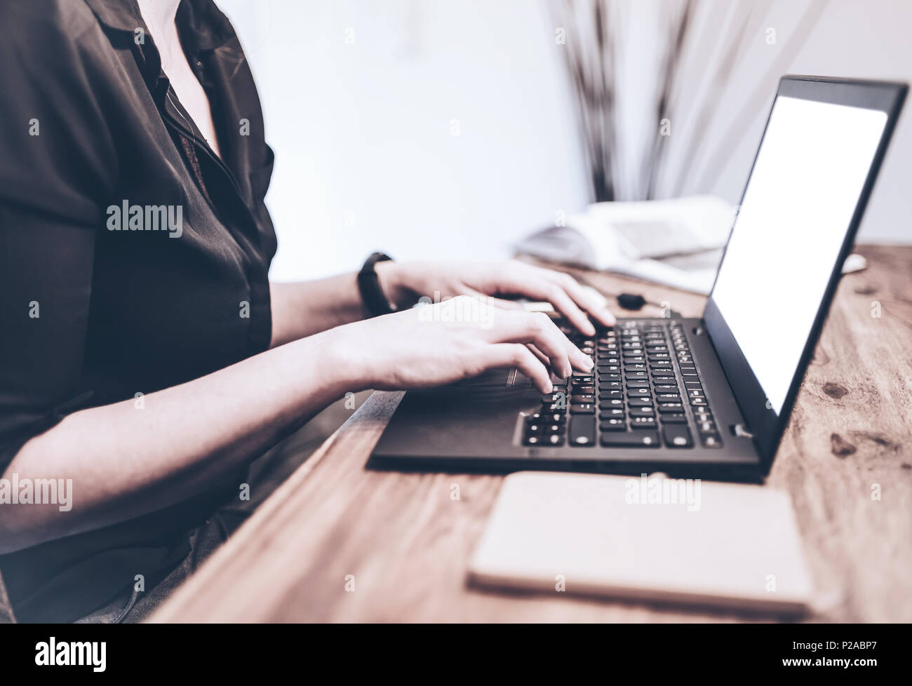 close-up of young woman working on laptop computer on wooden desk Stock Photo