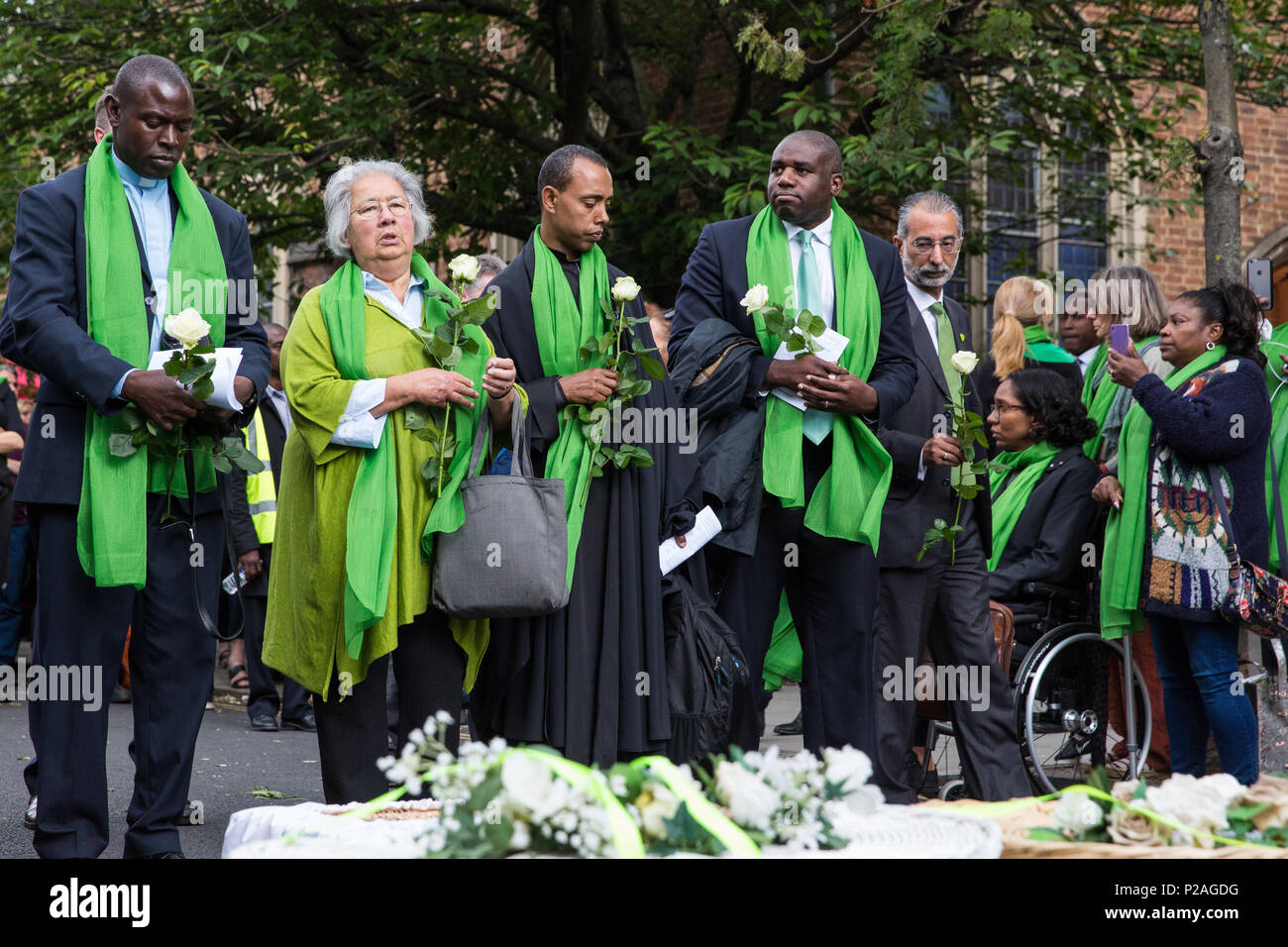 London, UK. 14th June, 2018. Faith leaders and politicians hold flowers outside St Helen's Church before doves are released to mark the first anniversary of the Grenfell Tower Fire. Stock Photo