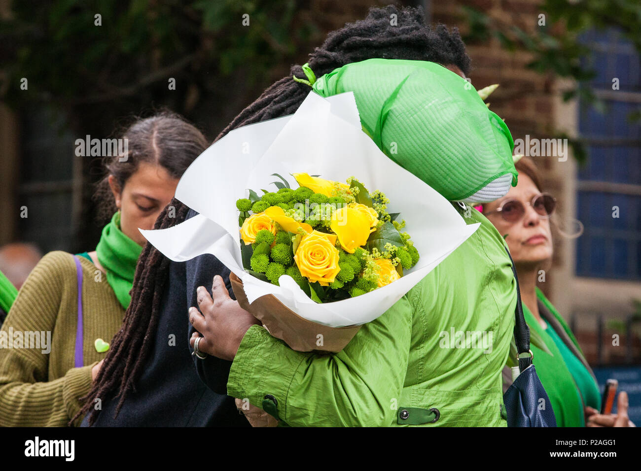 London, UK. 14th June, 2018. Members of the local community embrace as they prepare to release doves of peace outside St Helen's Church to mark the first anniversary of the Grenfell Tower Fire. Stock Photo