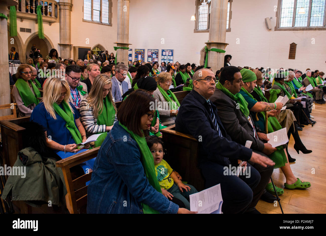 The congregation all wearing green scarves while attending the service to mark the Grenfell Fire anniversary in St Helen's Church, North Kensington, London, England, UK, 14th June, 2018 Stock Photo