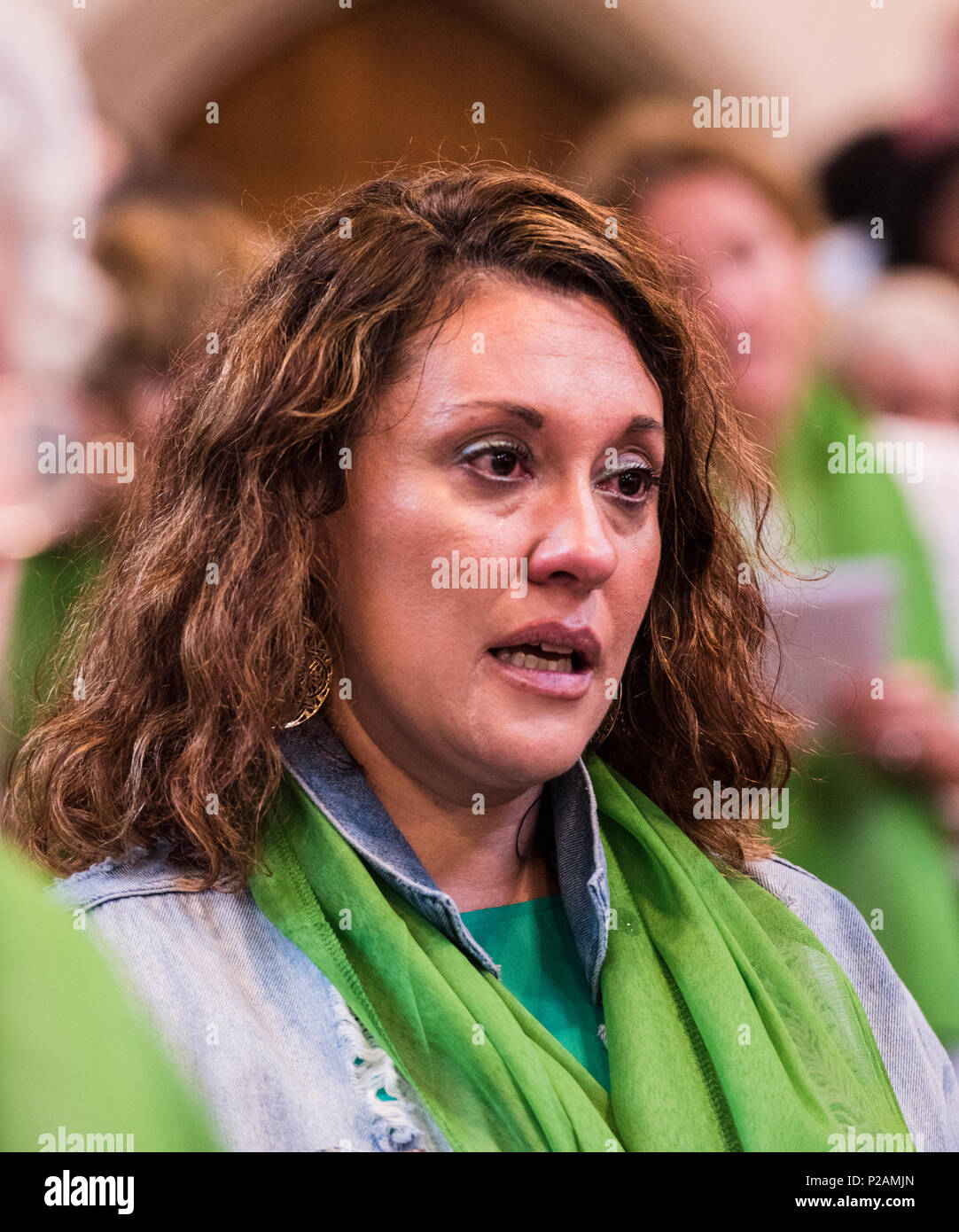 A woman cries while singing along at the service to mark the Grenfell Fire anniversary in St Helen's Church, North Kensington, London, England, UK, 14th June, 2018 Stock Photo