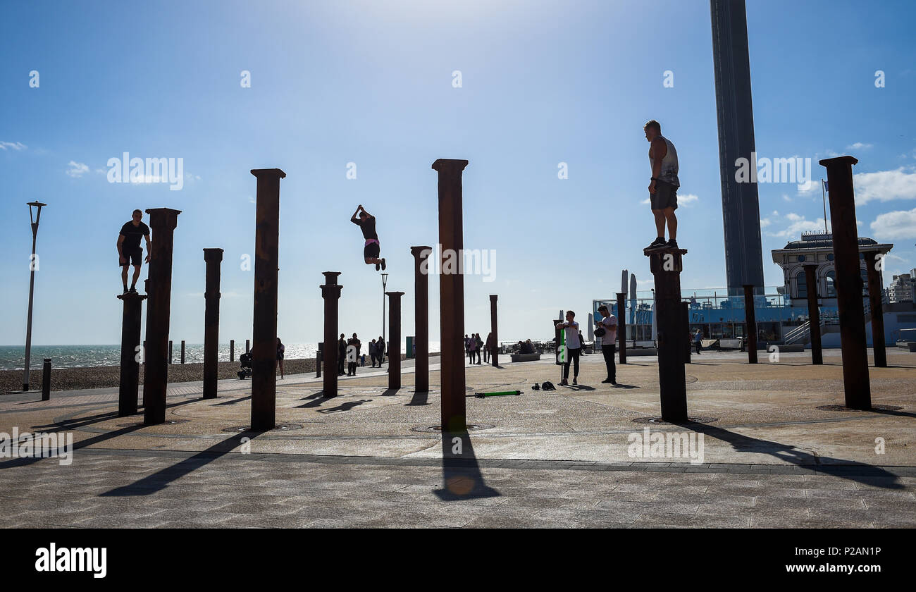 Brighton UK 14th June 2018 - Parkour performers leap across the pillars of the Golden Spiral installation beside the West Pier on Brighton seafront on a glorious sunny evening Photograph by Simon Dack Credit: Simon Dack/Alamy Live News Stock Photo