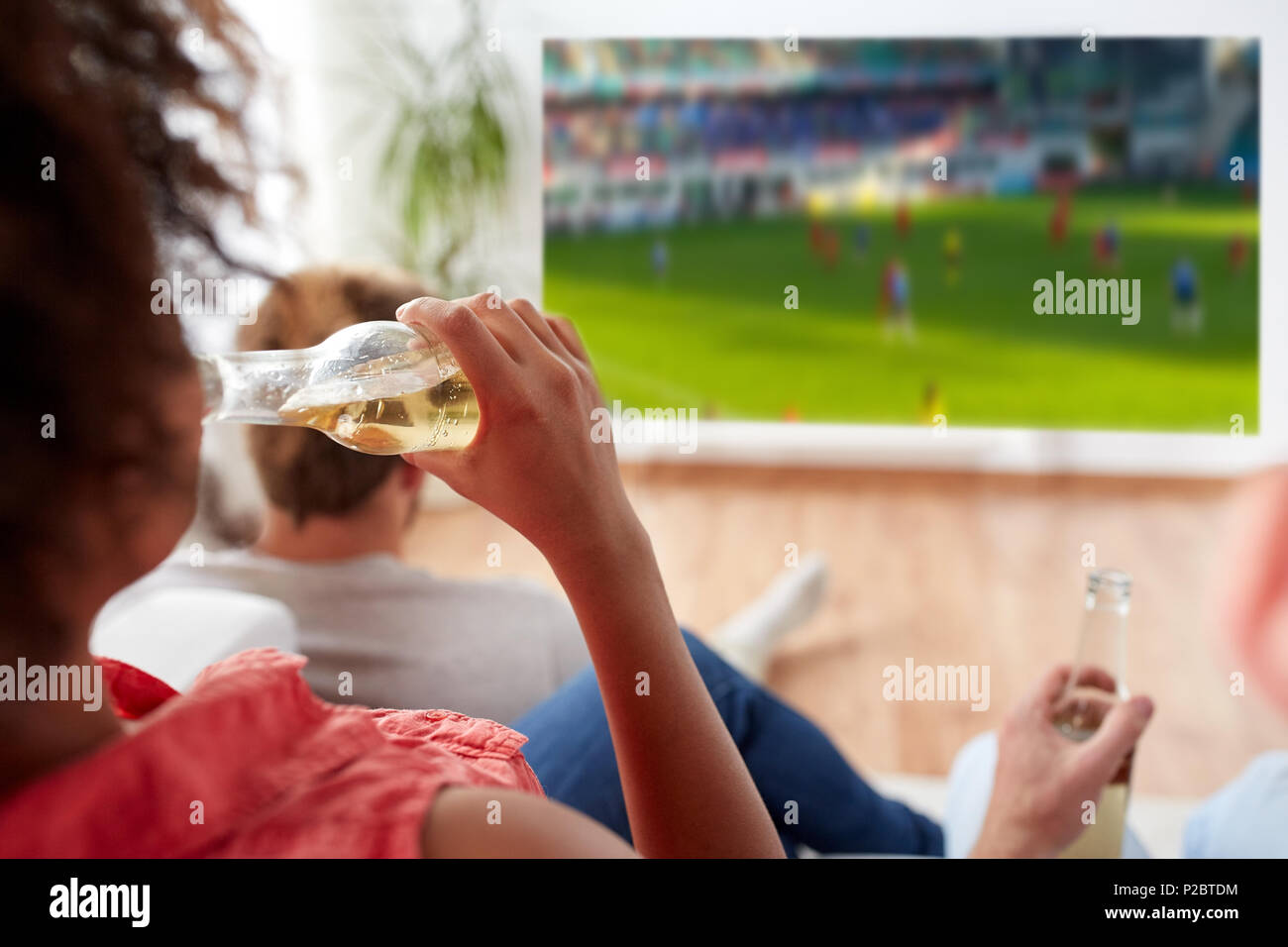 woman drinking beer and watching soccer game Stock Photo