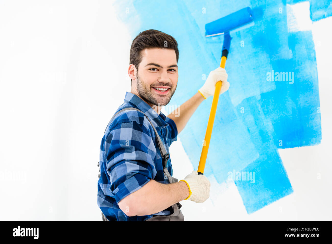 Smiling Handsome Man Painting Wall With Blue Paint P2BWEC 