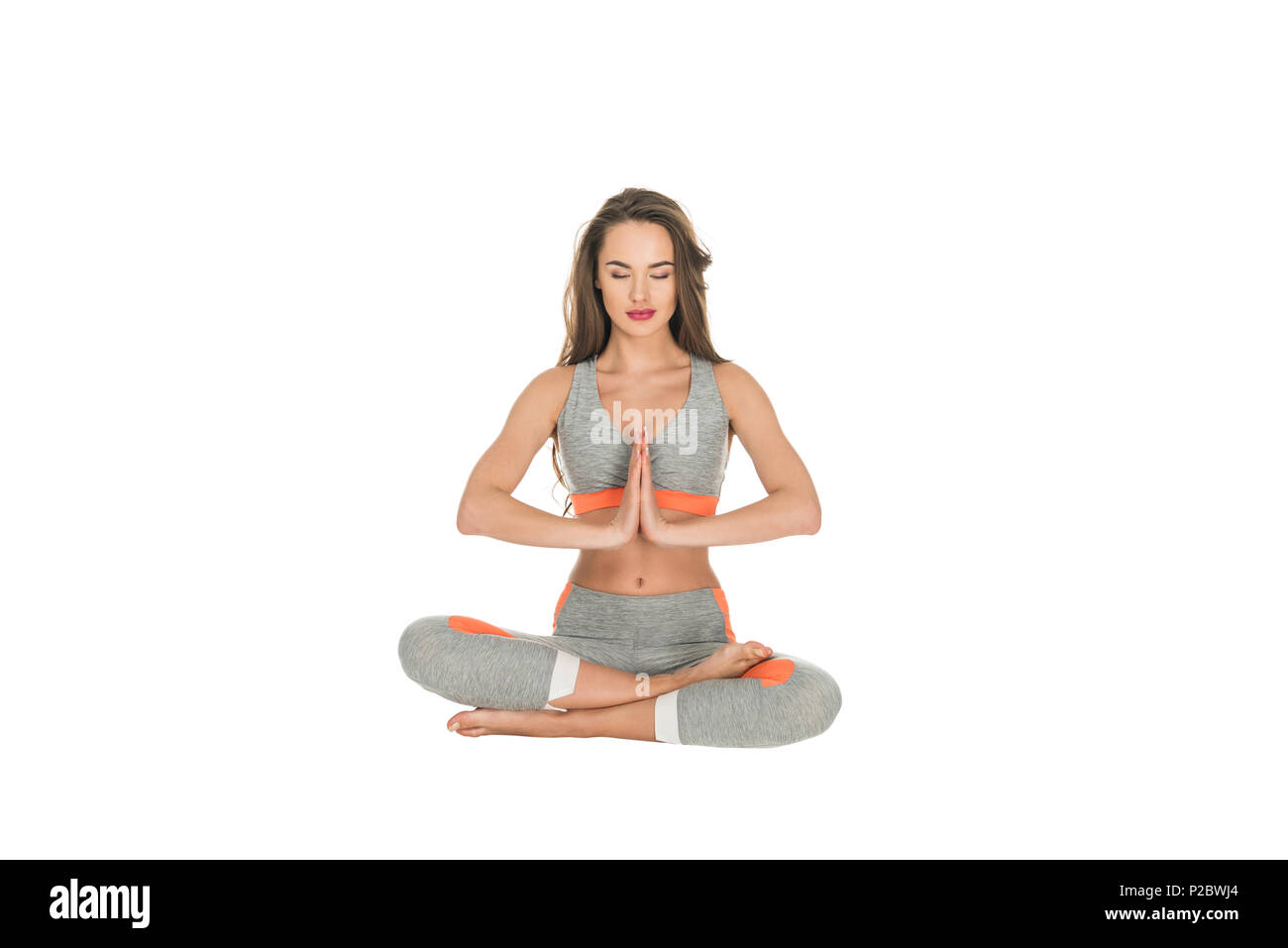 young woman with closed eyes sitting in lotus position isolated on ...