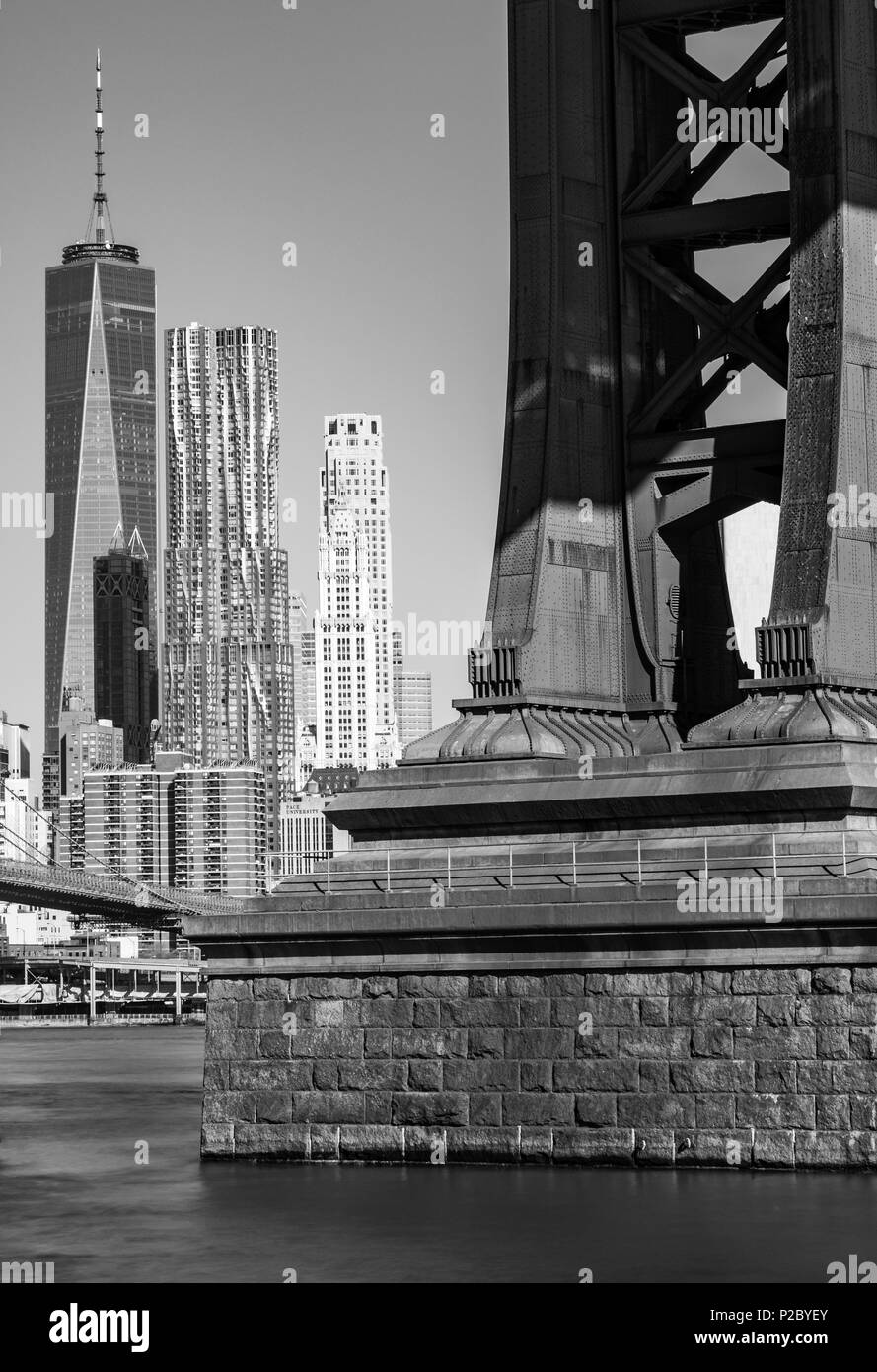 Black and white image of a metal and brick Manhattan Bridge pier with the Manhattan skyline and World Trade Center taken from Brooklyn, New York, USA Stock Photo