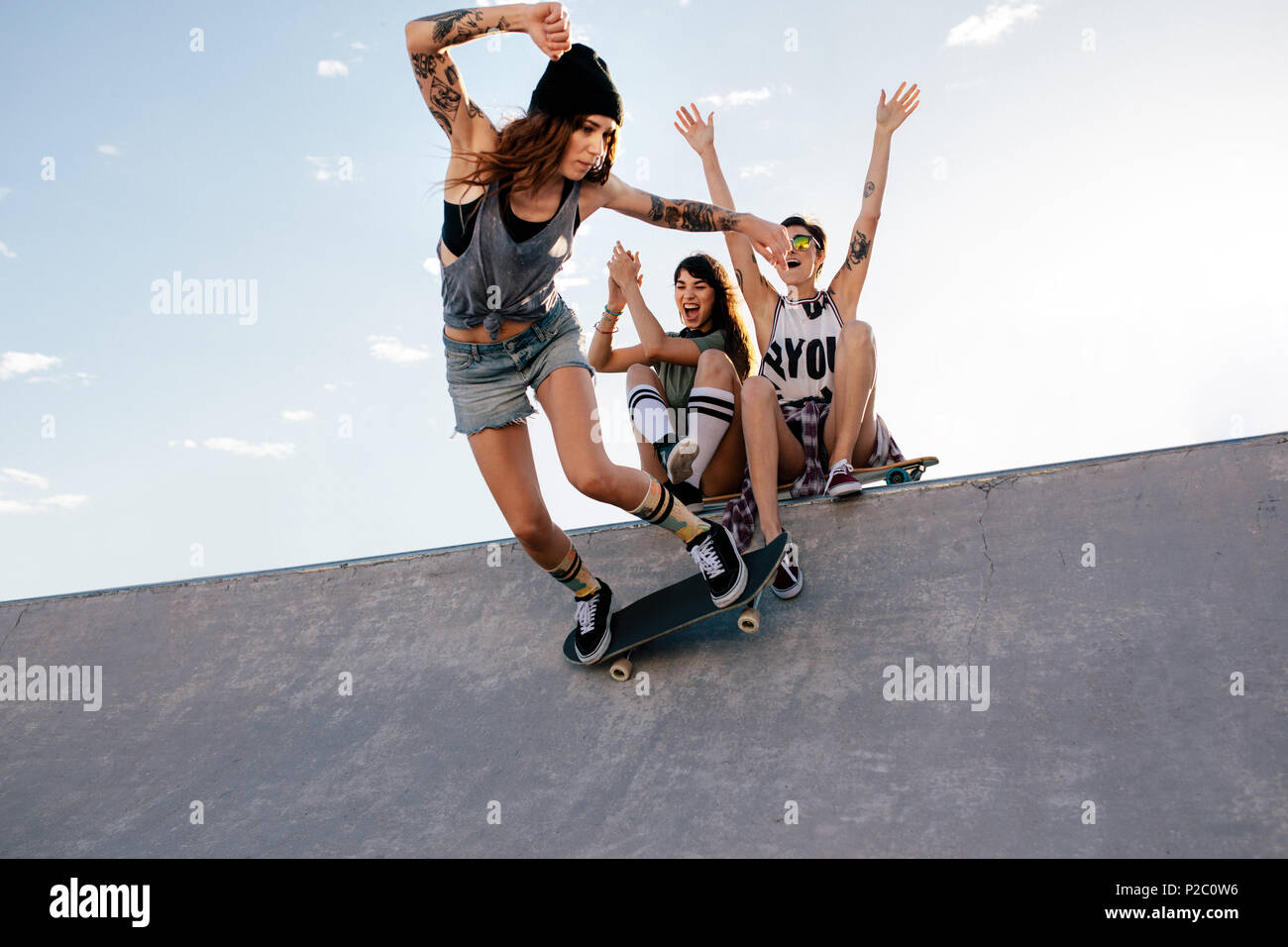 Skater girl rides on skateboard with female friends sitting on ramp  cheering. Female skateboarding at skate park with friends cheering Stock  Photo - Alamy