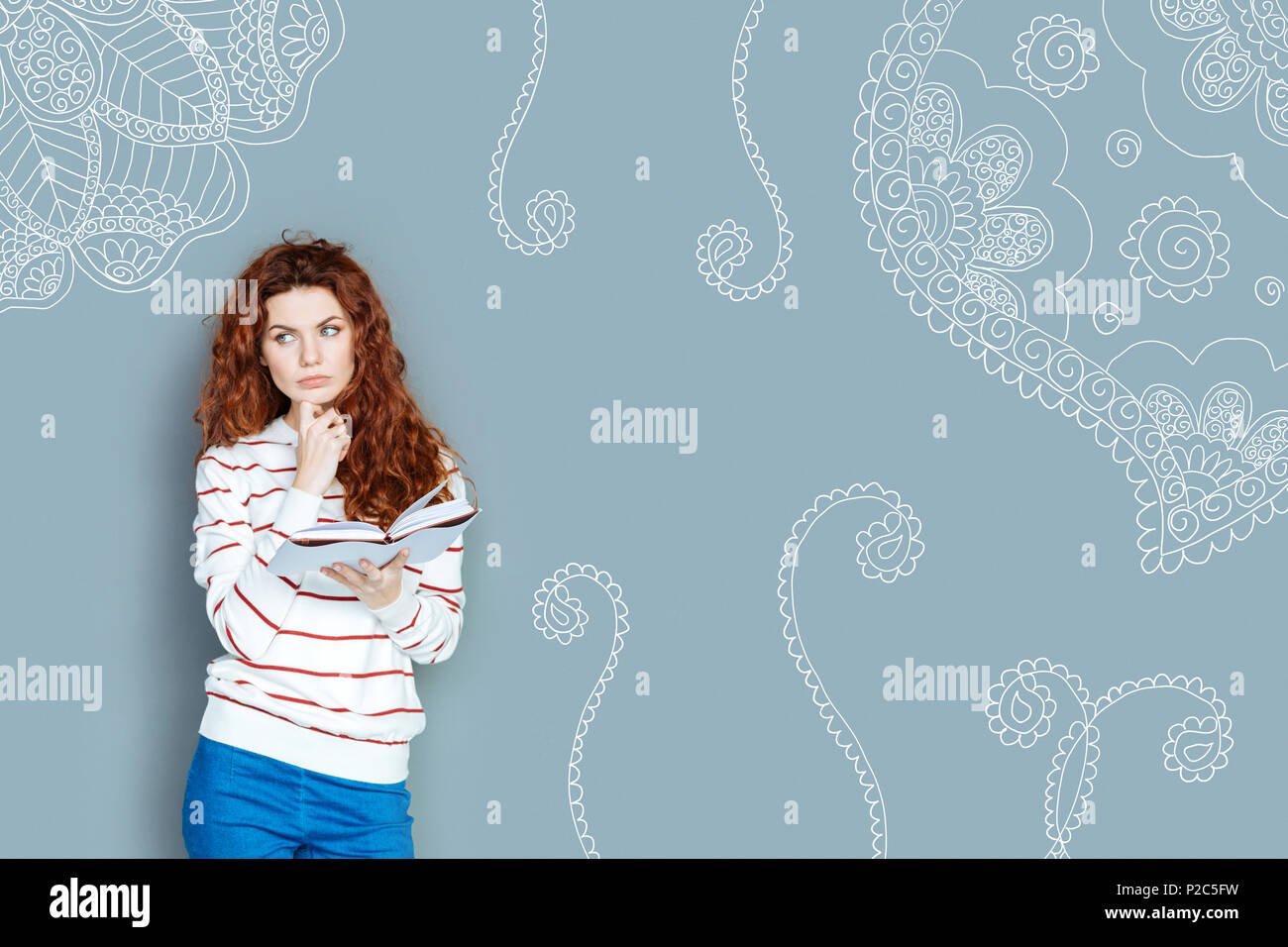 Thoughtful teacher looking into the distance while holding a book Stock Photo