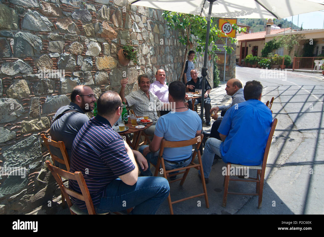 Men sitting at bar tables along the road in Gourri village about 30km westl of Lefkosia, Nicosia, Cyprus Stock Photo