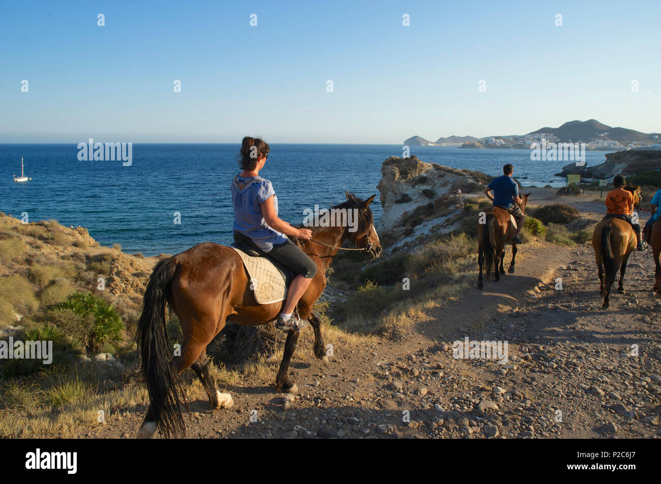 Tourists on horseback, horse riding from San Jose on the rocky coast of Cabo de Gata in the afternoon, Almeria province, Andalus Stock Photo