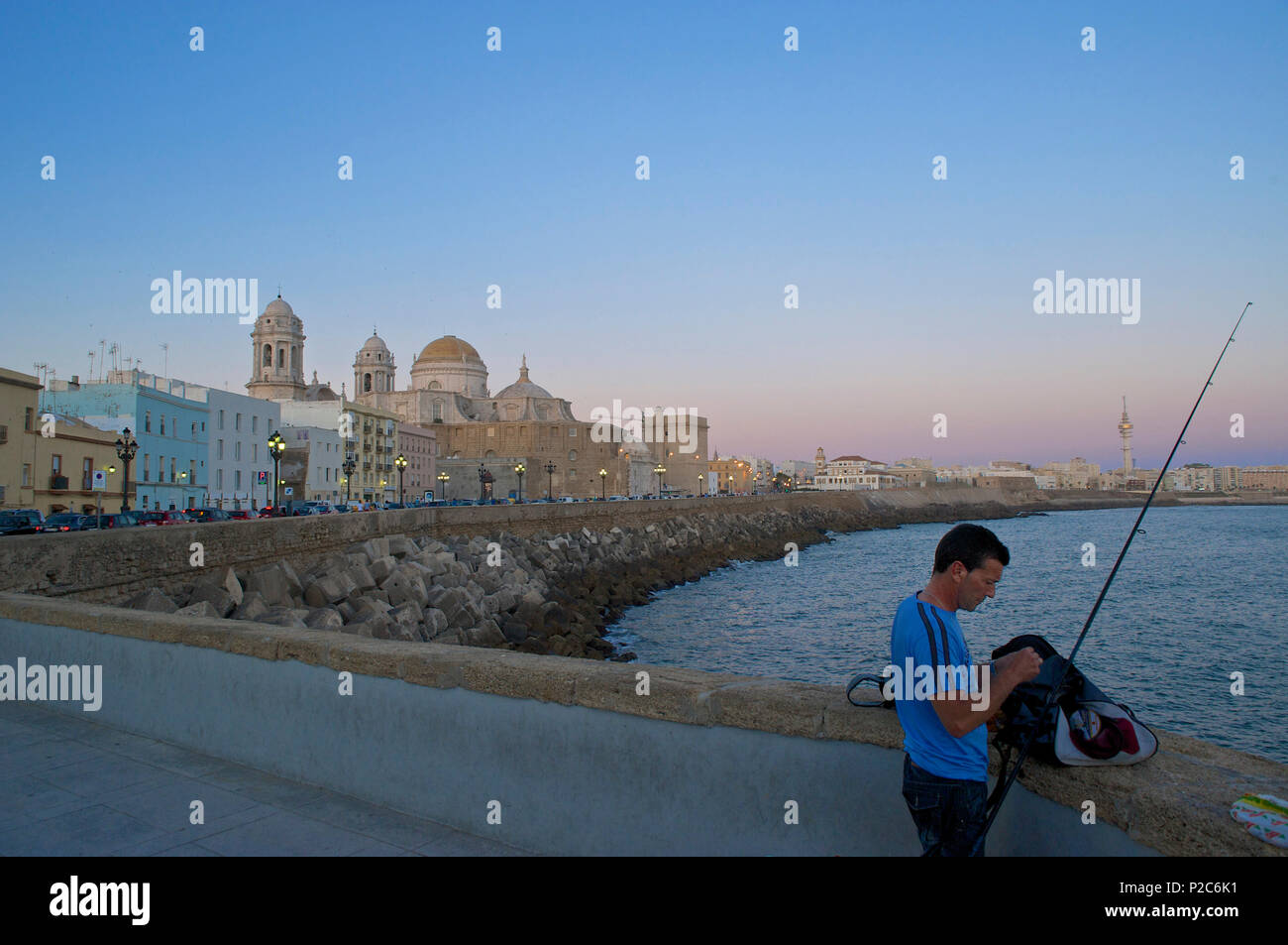 Man fishing from the promenade along the Av. Campo del Sur with wall and old style electric lights, view over the sea to the cat Stock Photo