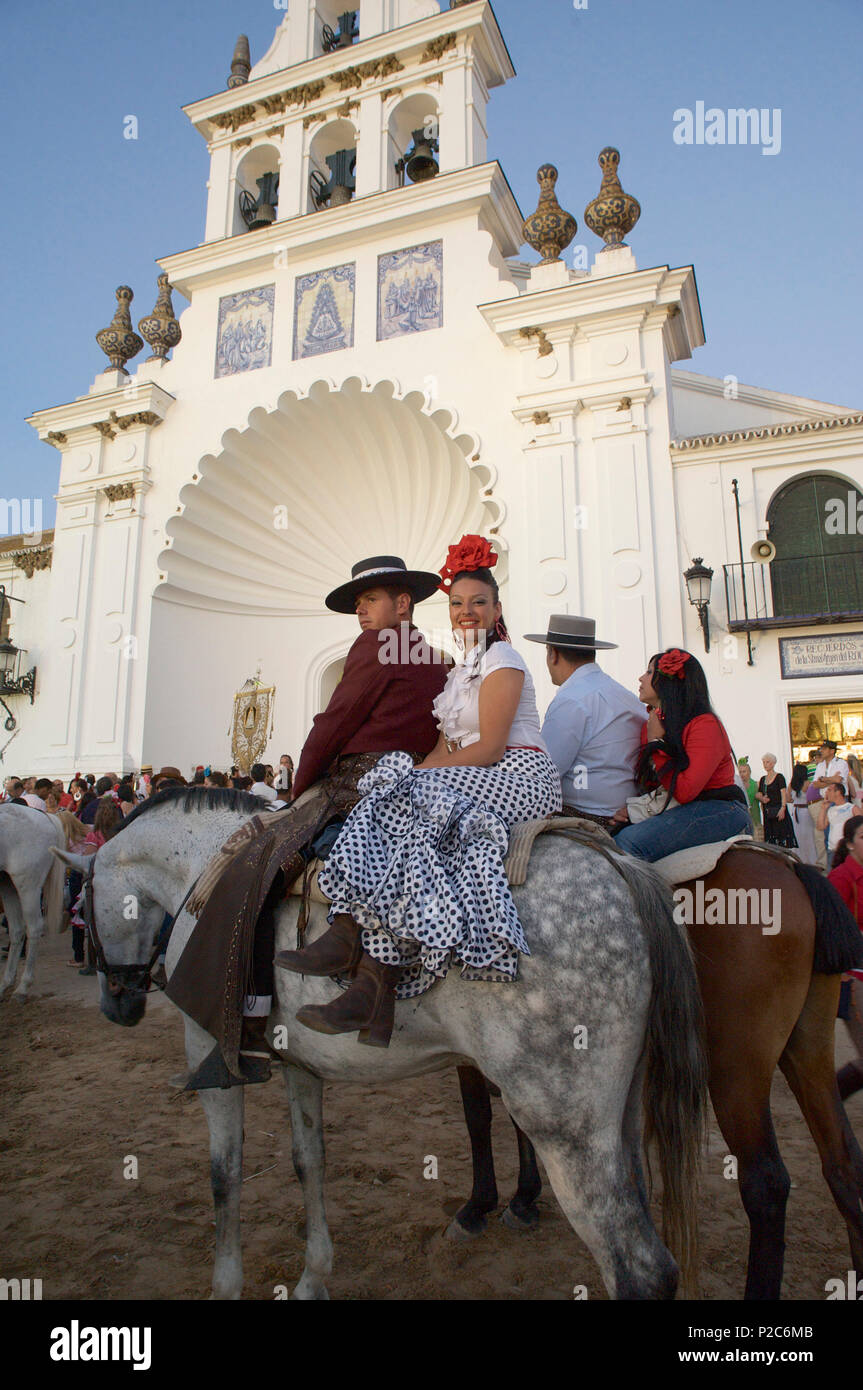 Couple on horseback in traditional dress in front of the church Eremita del Rocio at El Rocio at Pentecost, Huelva, Andalusien, Stock Photo