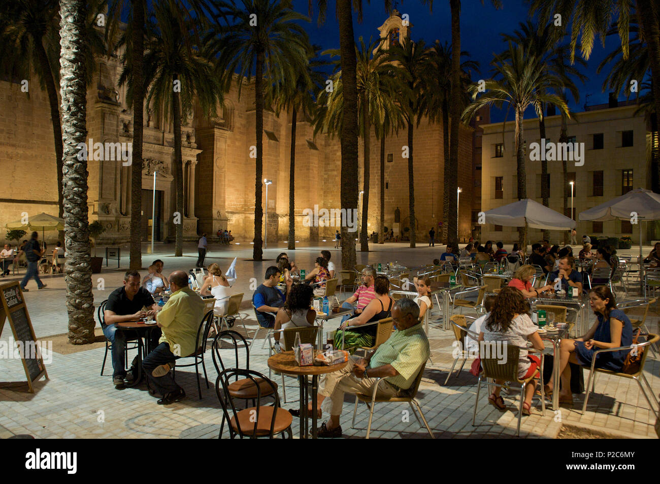 Plaza in front of the cathedral with palm trees and people at tables lit in the evening, Almeria, Andalusia, Spain Stock Photo