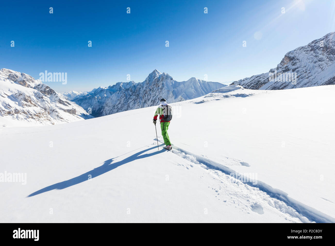 skier in deep powder snow, Zugspitze, overlooking Reintal Valley and Hochwanner, Upper Bavaria, Germany Stock Photo