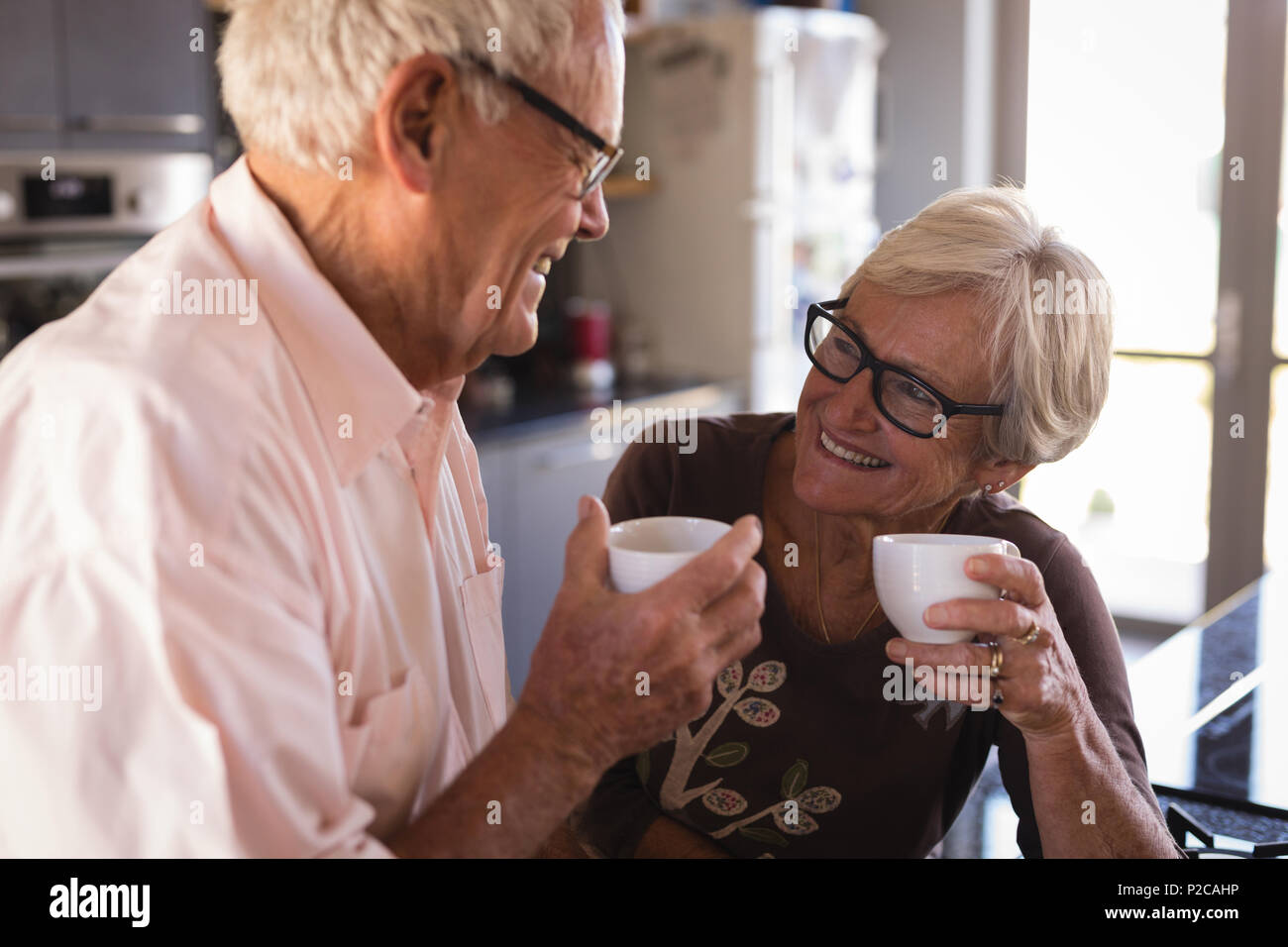 Senior couple smiling while having coffee in kitchen Stock Photo
