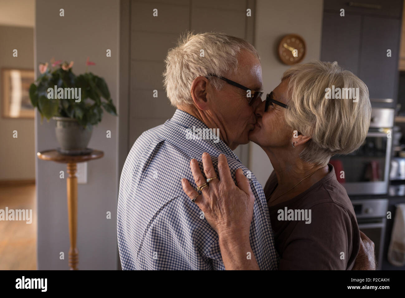 Beautiful senior couple kissing in kitchen Stock Photo