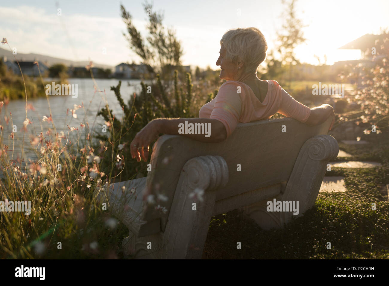 Senior woman relaxing on bench near riverside Stock Photo