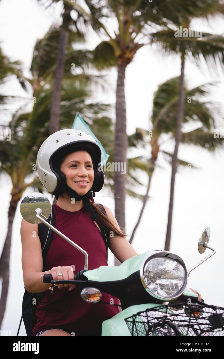 Woman riding scooter in city street Stock Photo