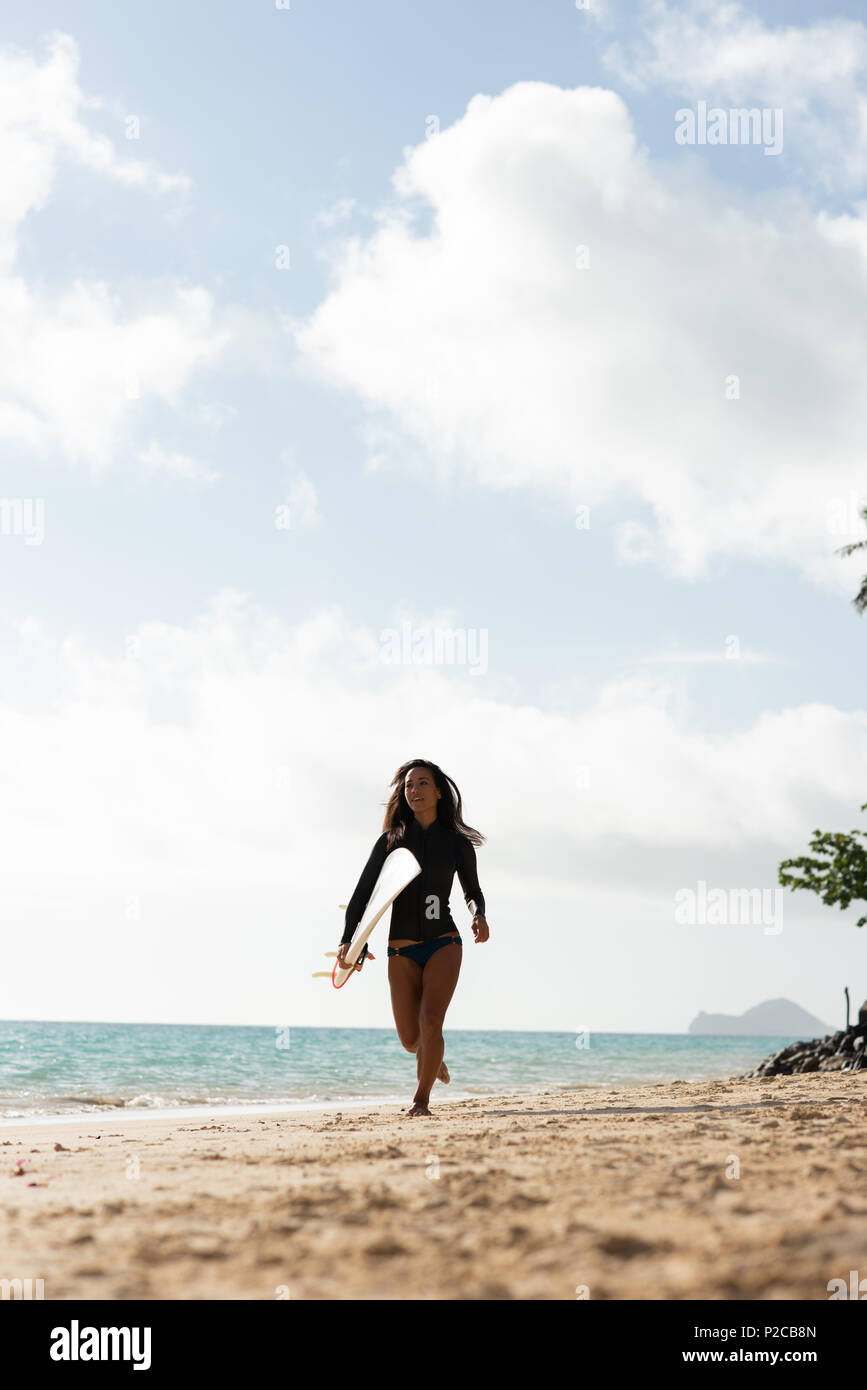 Woman running with surfboard in the beach Stock Photo
