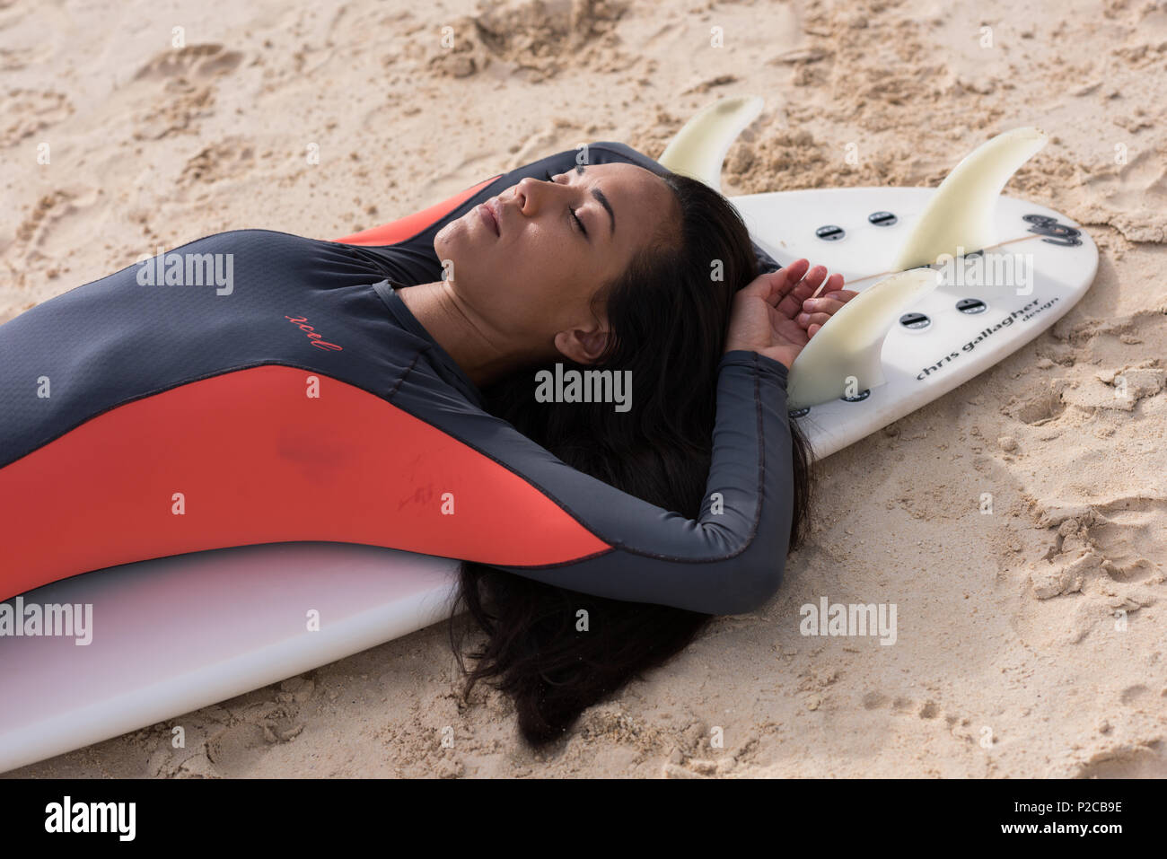 Woman sleeping on surfboard in the beach Stock Photo