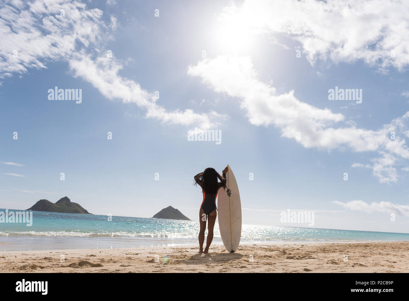 Woman standing with surfboard in the beach Stock Photo